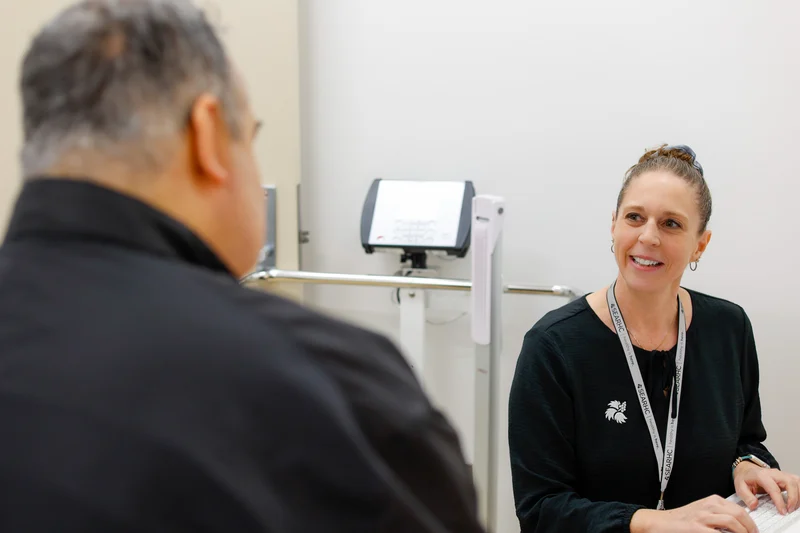 A smiling female healthcare professional talks to a male patient in a clinic.