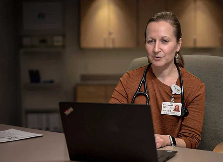 A female medical professional is on a teleheatlh appointment on a laptop in a medical office.